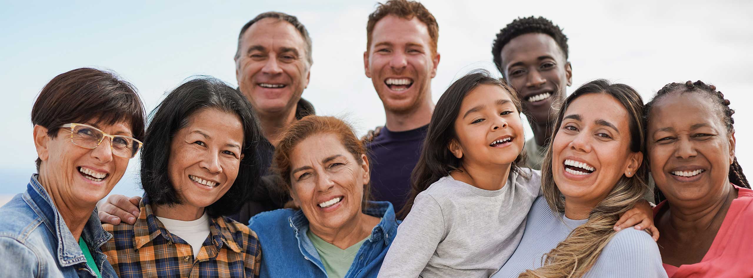 Diverse group of smiling adults and families enjoying time together outdoors — representing compassionate, inclusive family practice and primary care in Phoenix, AZ.